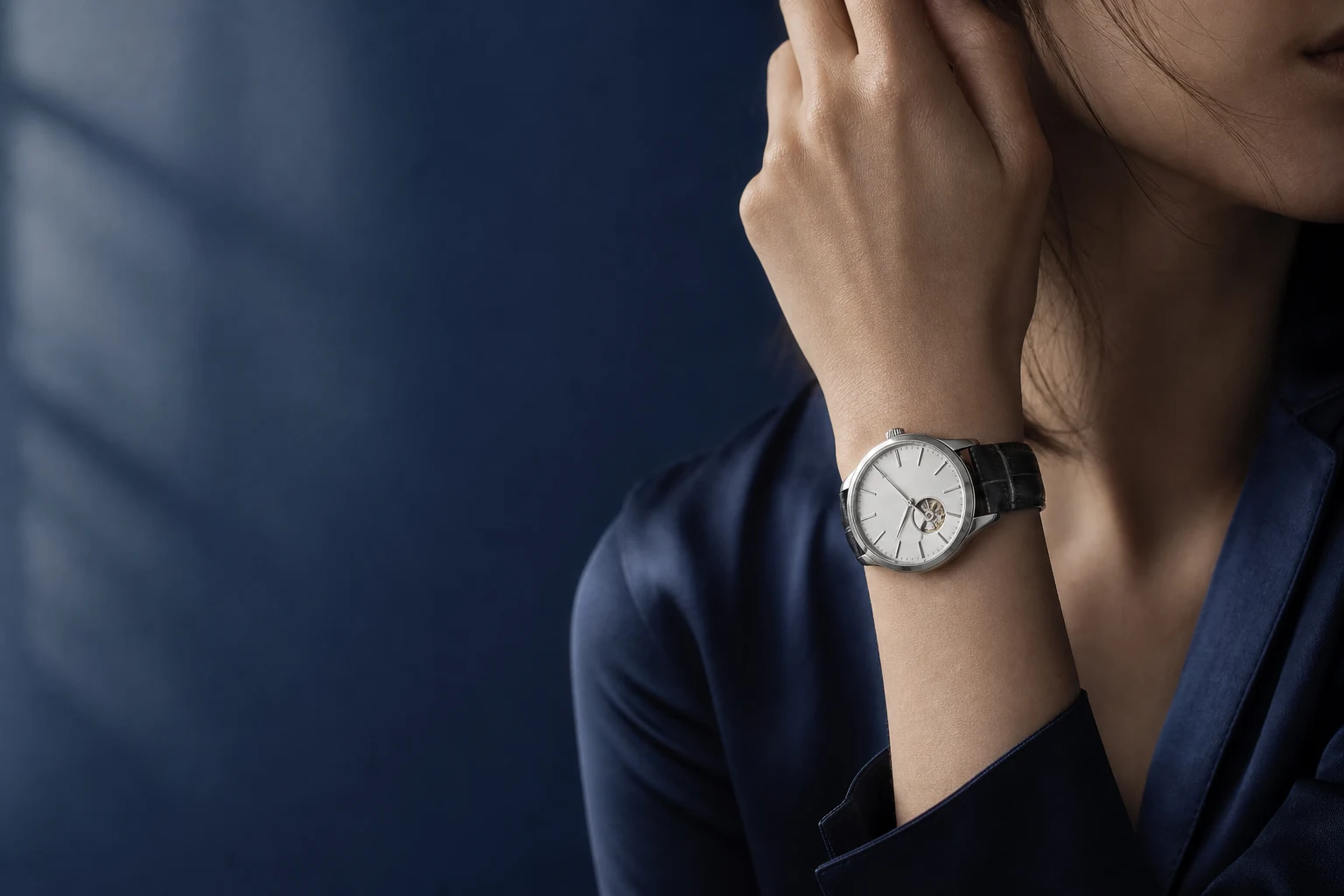 A silver-dial Méridienne watch on a wrist, midnight-blue backdrop
